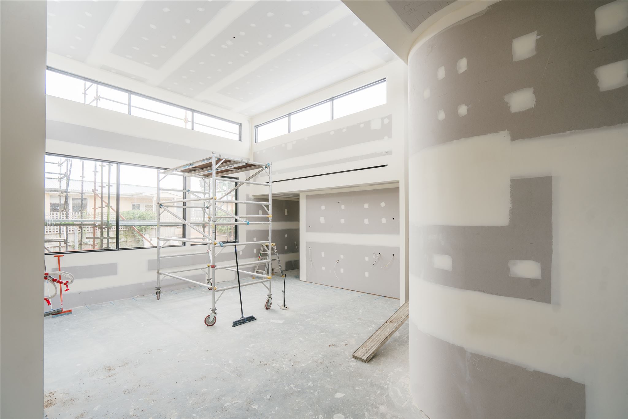 Open-plan room with set plasterboard walls, a curved column and a mobile scaffold
