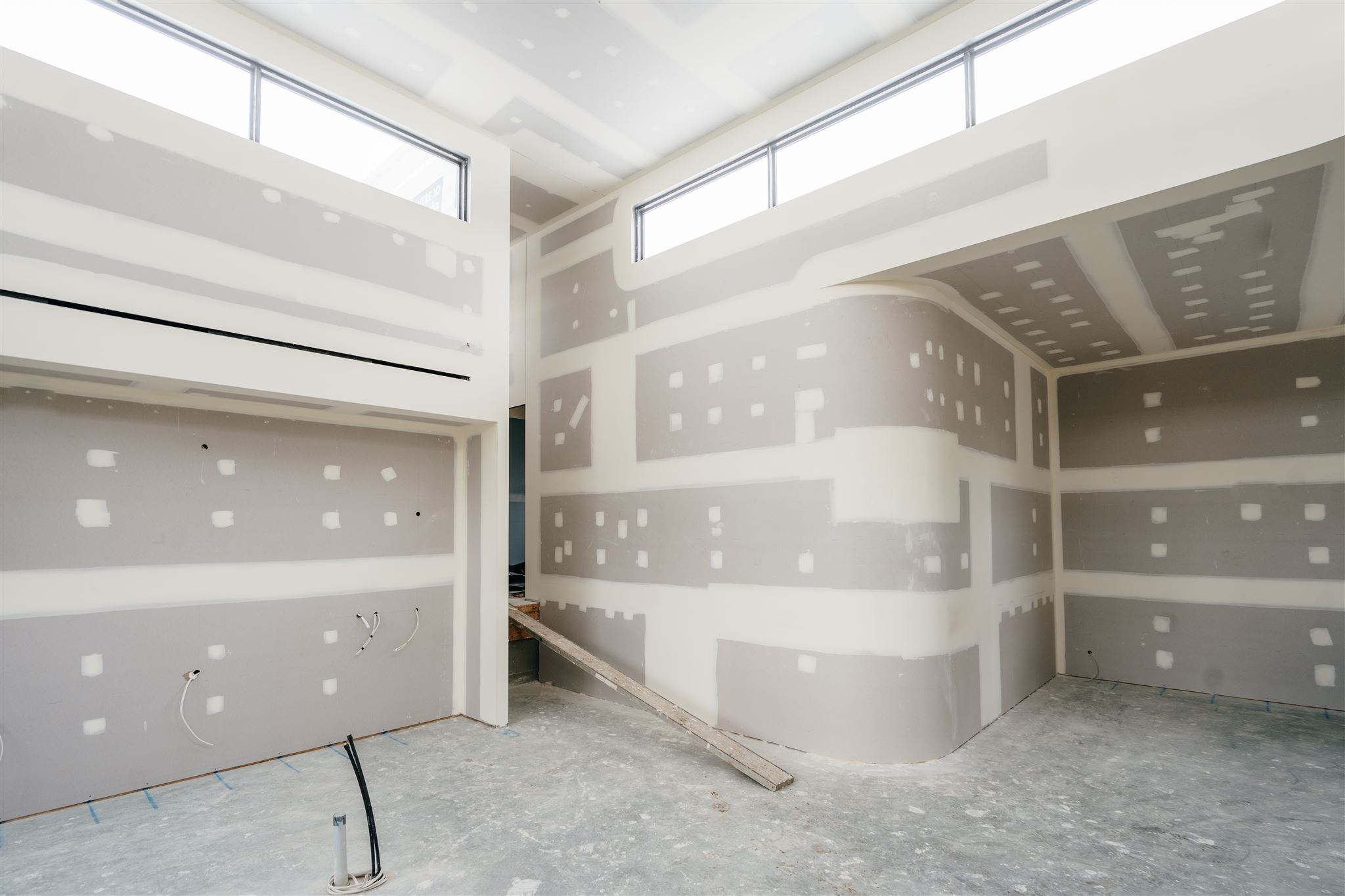 Room corner with set plasterboard, a curved recess and highlight windows above