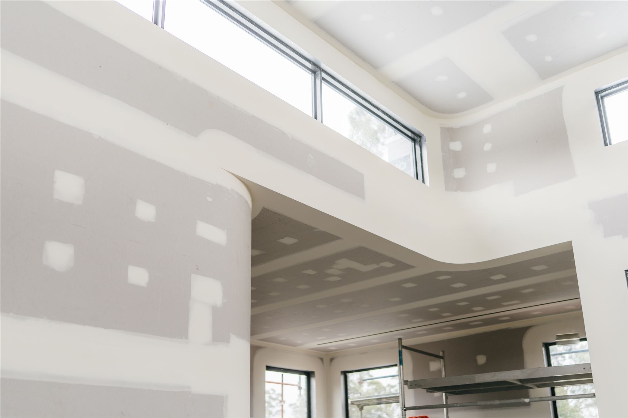 Looking up at a curved plasterboard bulkhead under tall highlight windows