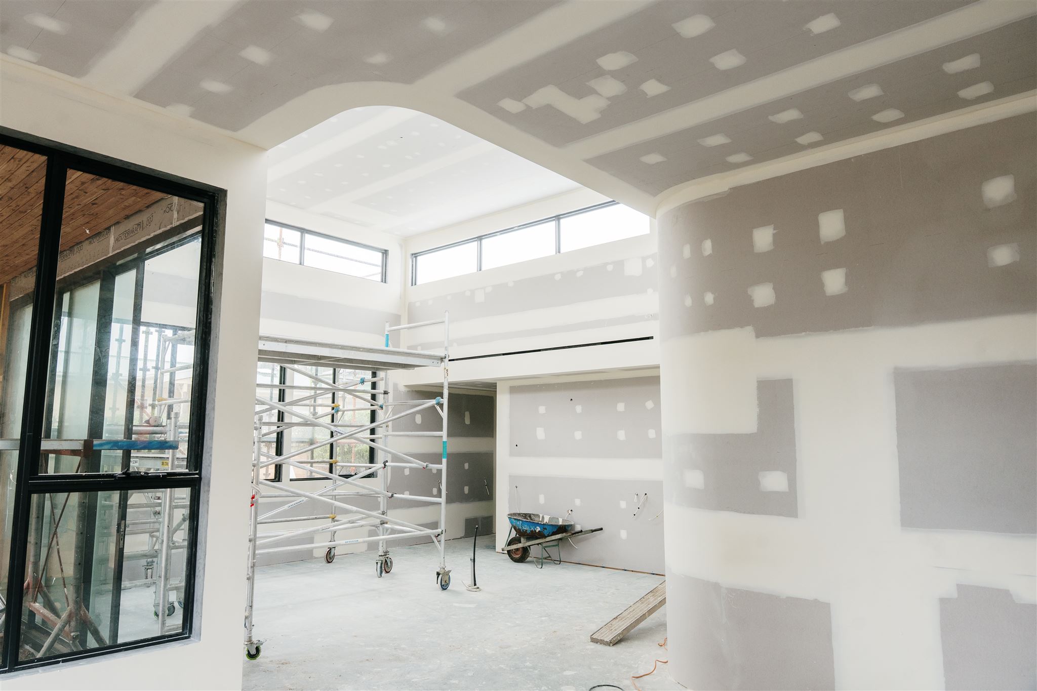 Curved bulkhead beside a black-framed window, with set walls and scaffolding behind