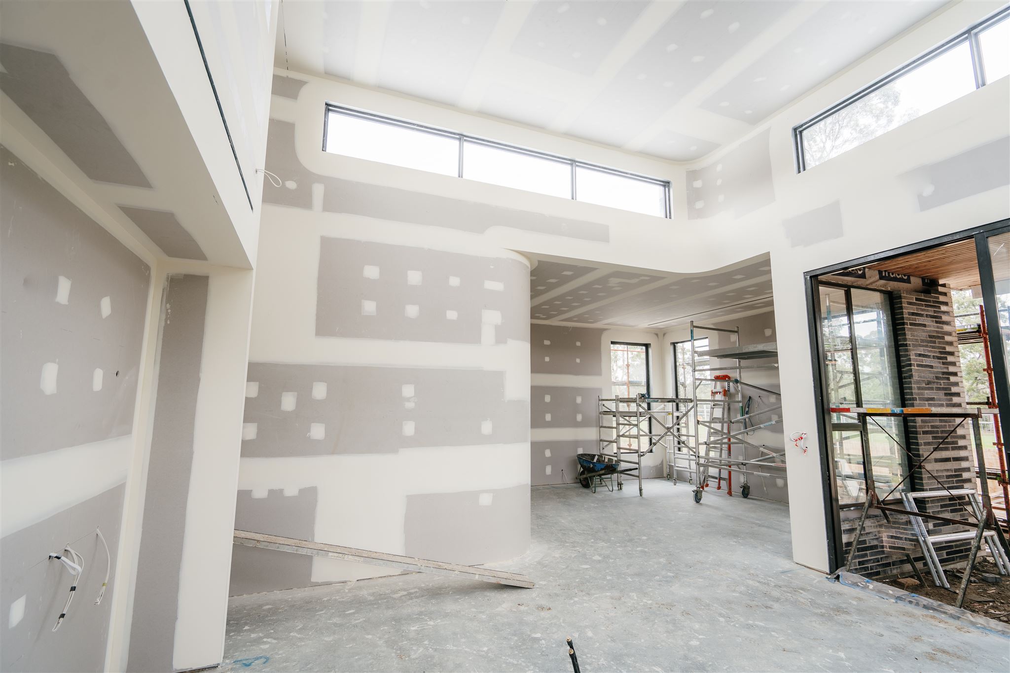 Wide view of an open-plan room with curved set plasterboard walls and scaffolding