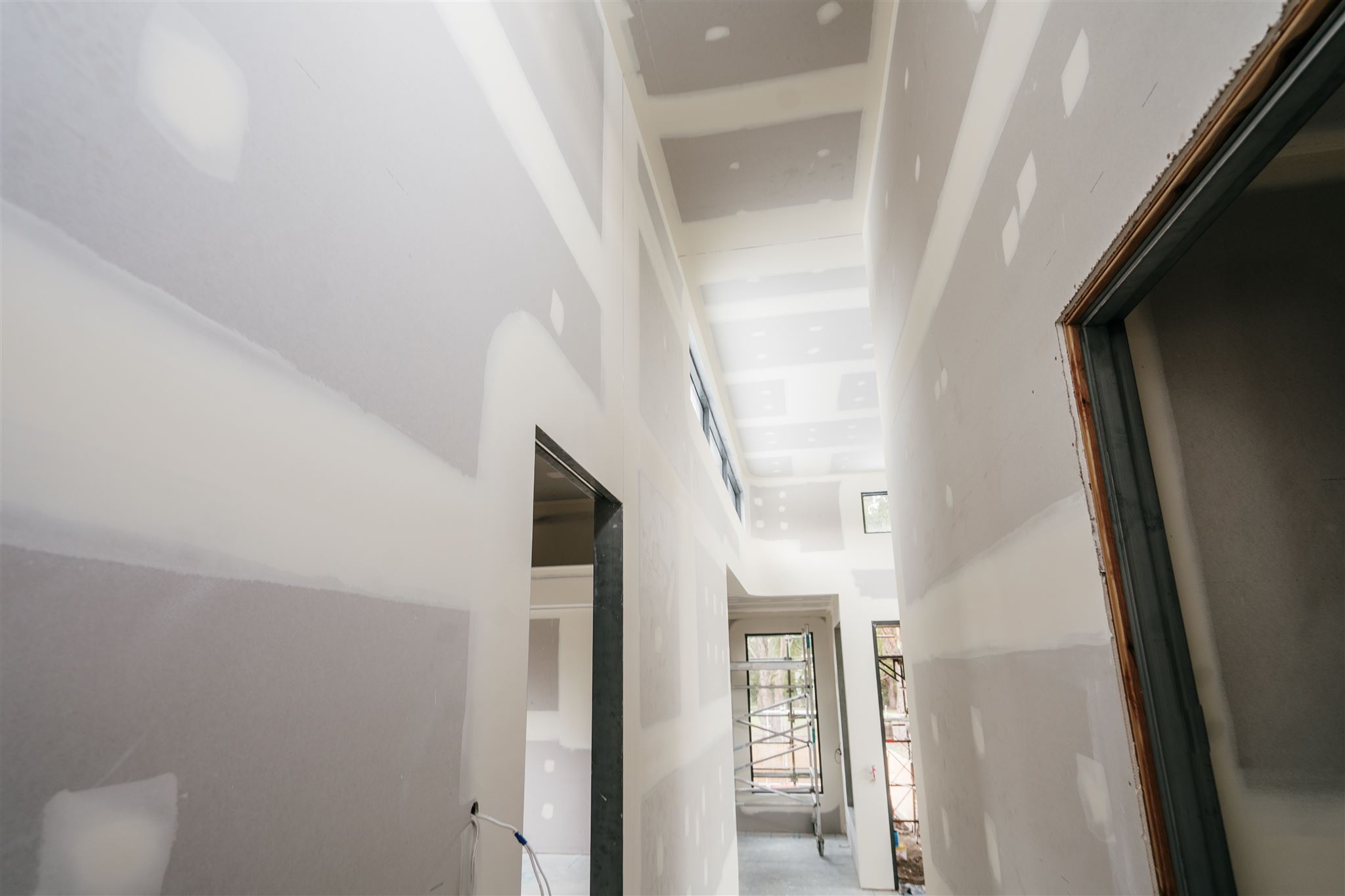 Tall hallway with set plasterboard walls and a dark door frame