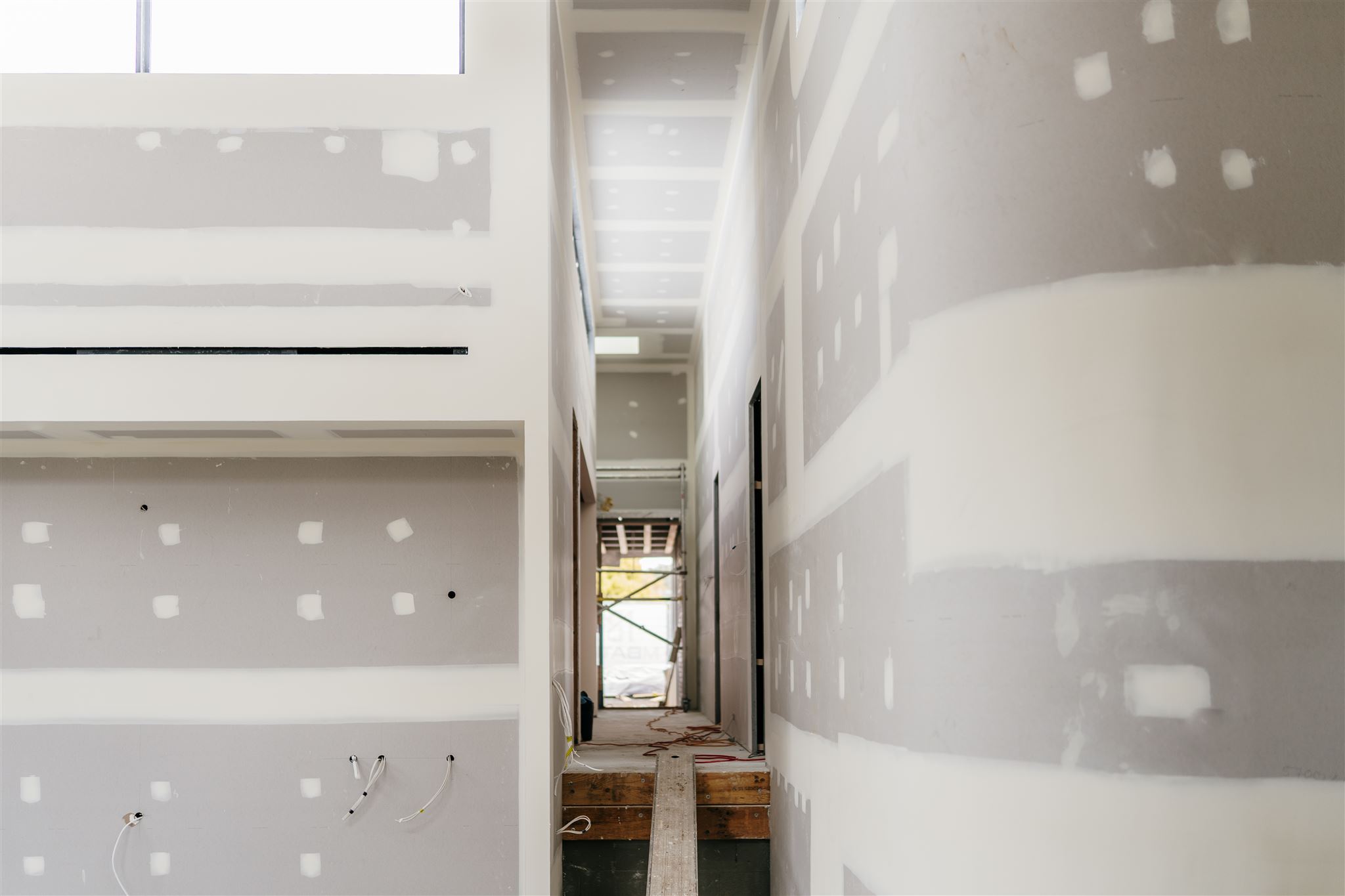 Narrow corridor between set plasterboard walls, with a curved wall on the right