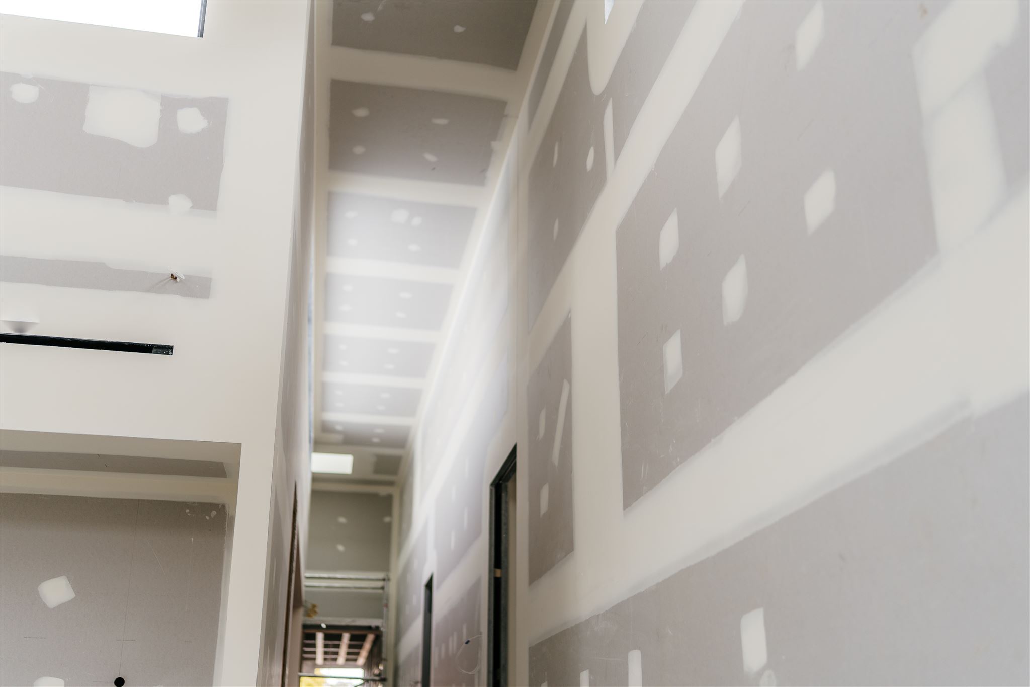 Looking down a tall hallway with set plasterboard walls and ceiling