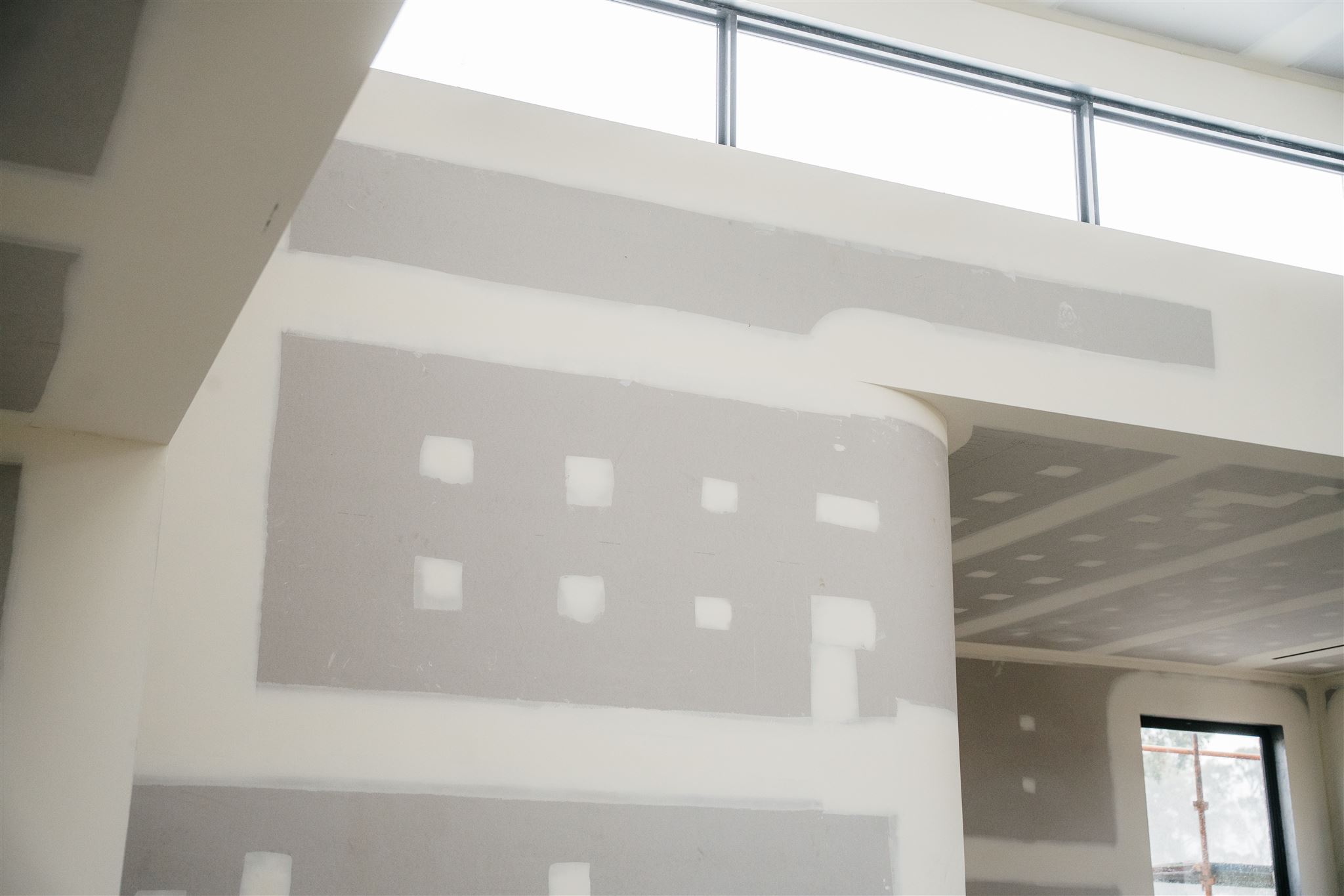 Close view of a curved plasterboard corner under highlight windows